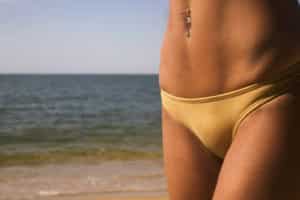 fit woman in yellow bikini at the beach