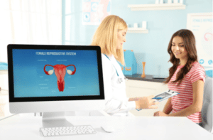 Computer at hospital on blurred gynecologist and woman