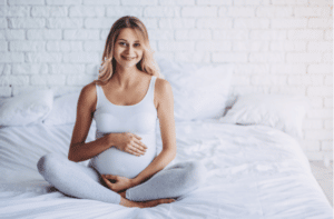 Attractive pregnant woman is sitting in bed